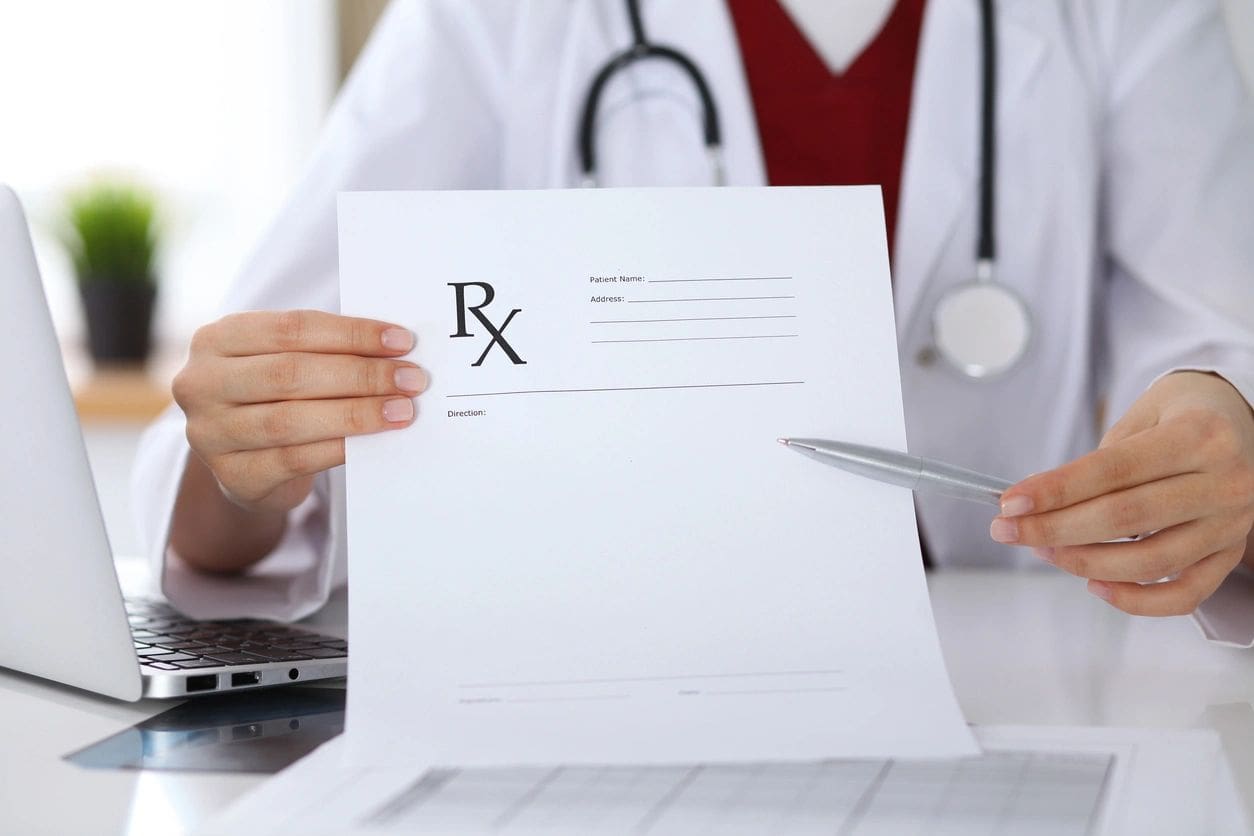 A person holding a pen and paper with a rx sign on it.