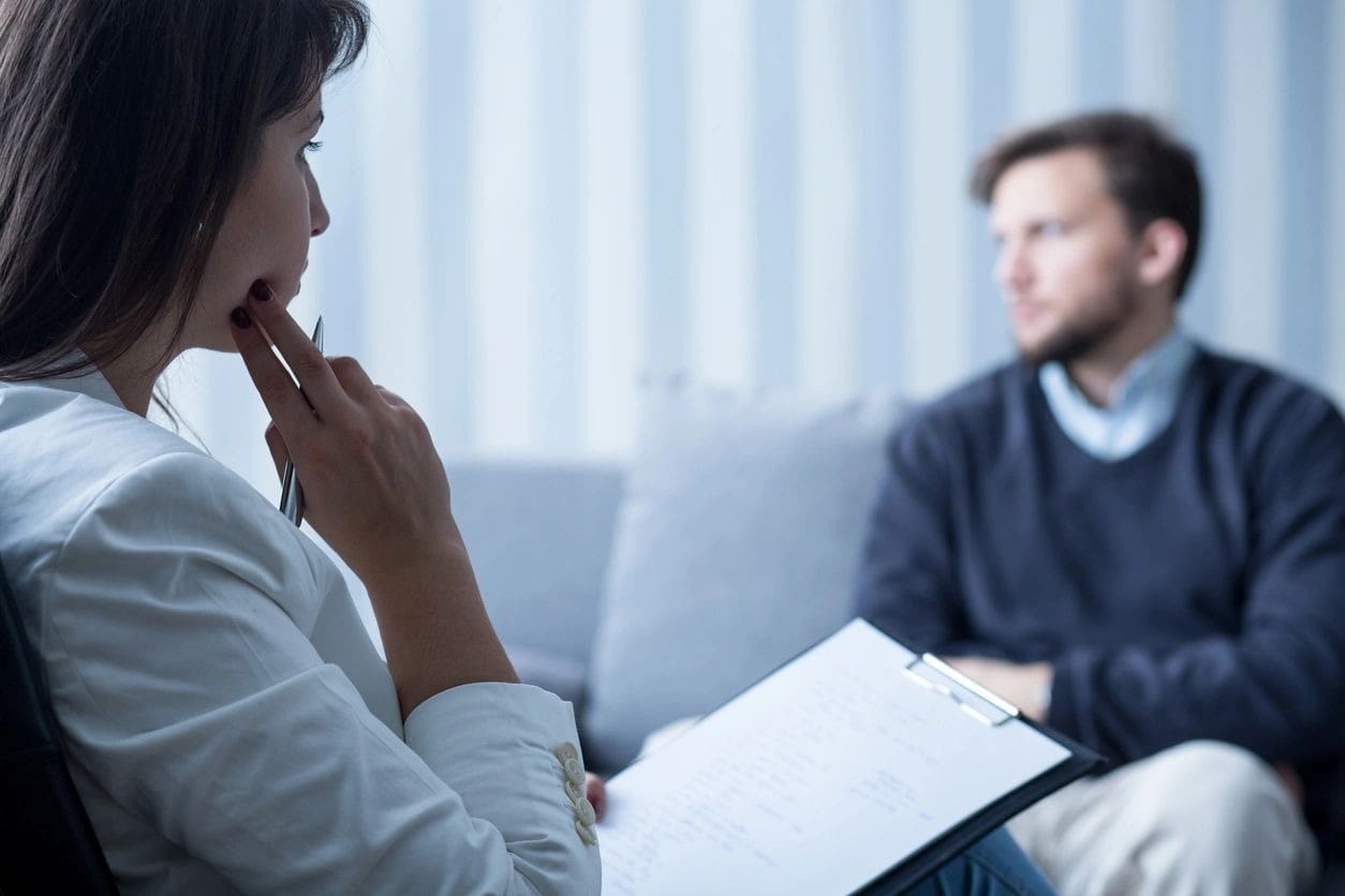 A woman sitting on the couch with another man.