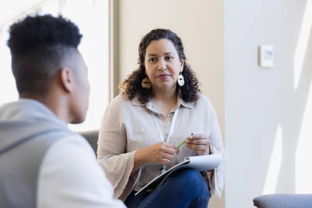 A woman sitting in front of another man.