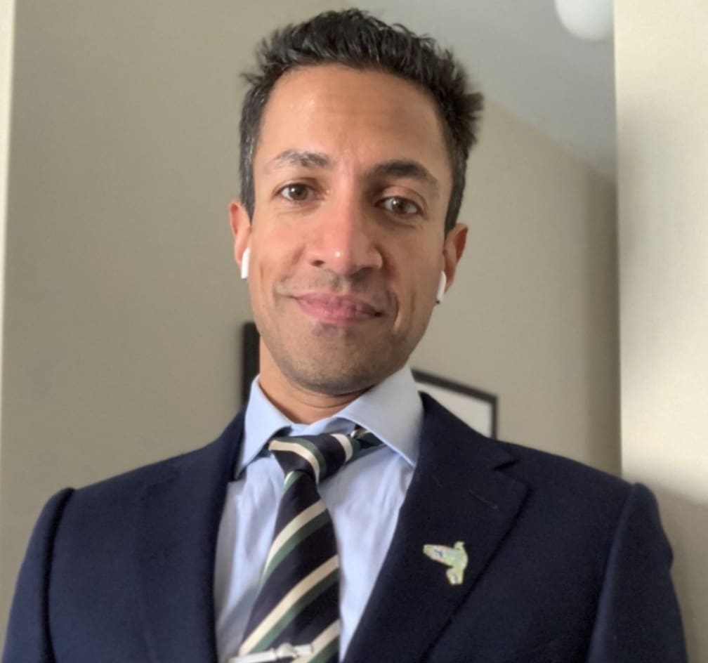 A man in a suit and tie standing next to a mirror.