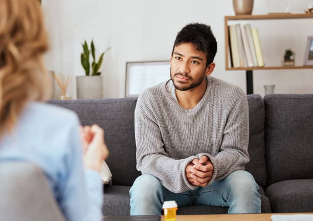 A man sitting on the couch with another person.